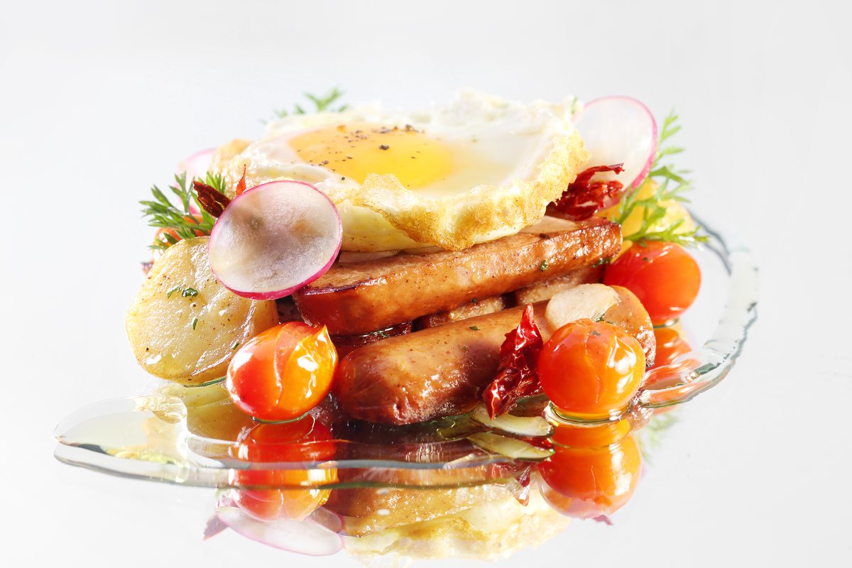 Grilled sausage with fried egg, potato and tomatoes